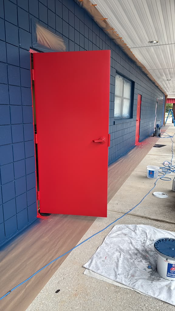 Red commercial door on blue exterior wall