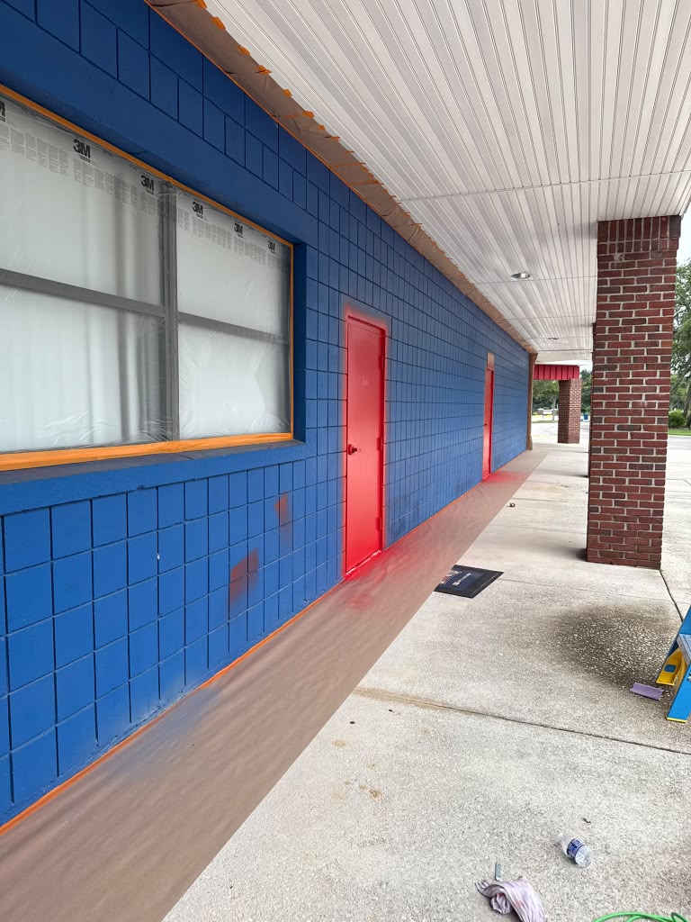 Red metal building exterior with equipment staged on-site